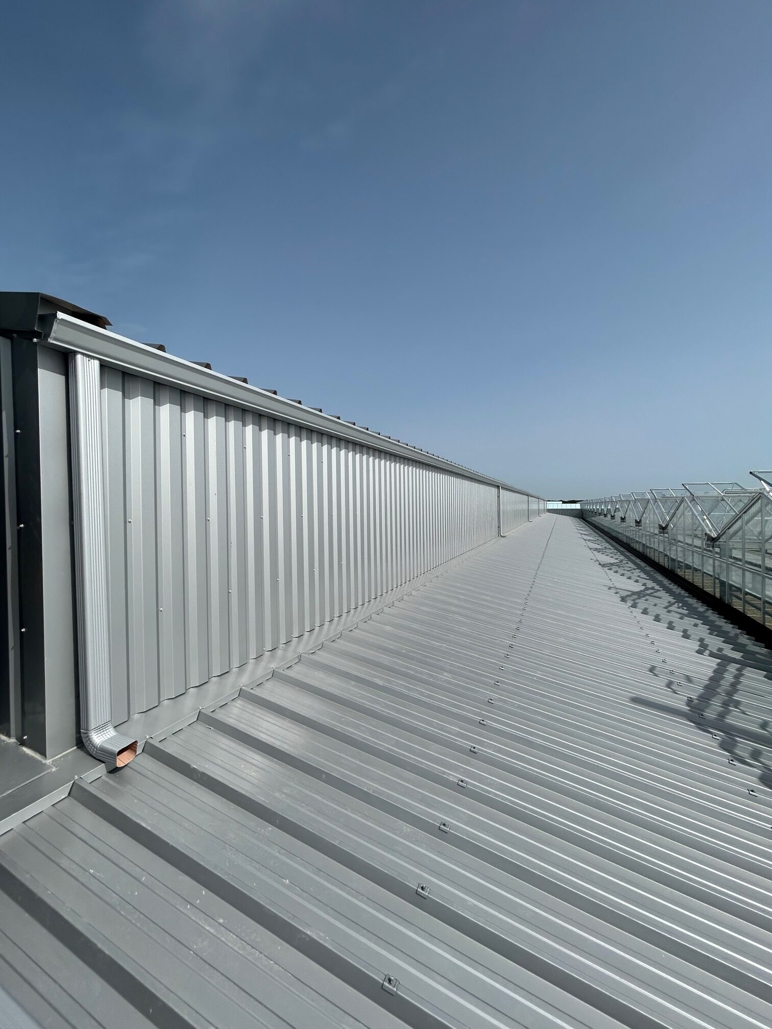 Installation de gouttières en G400 corniche pour un bâtiment industriel en couleur gris alu ral 9006